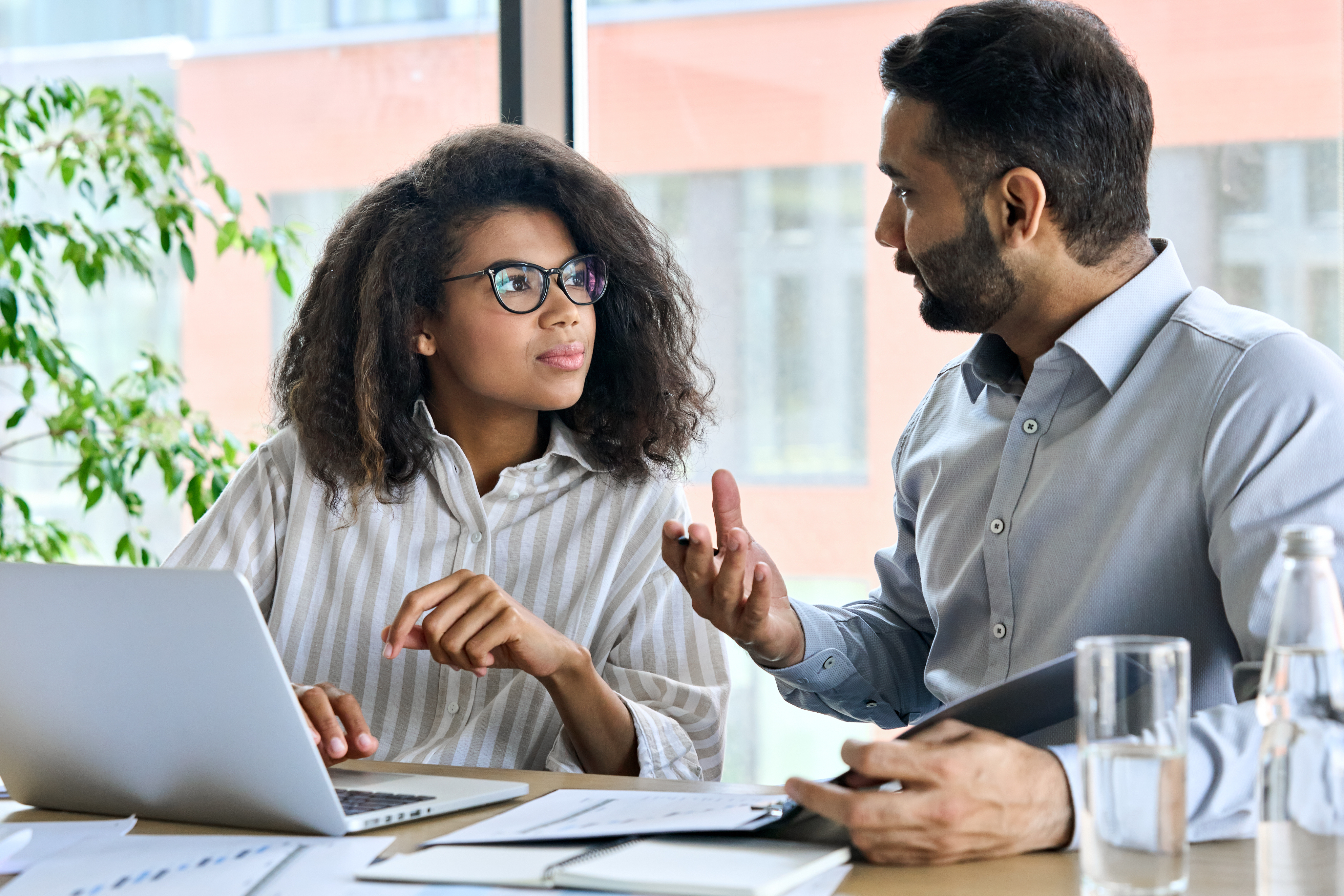 Lady Wiht A Laptop In Discussion With A Man Holding A Pen And Note Pad